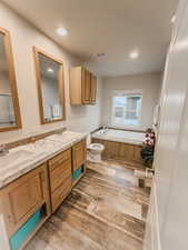 Bathroom featuring hardwood / wood-style floors, vanity, toilet, and a tub