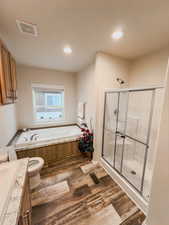 Full bathroom featuring hardwood / wood-style flooring, toilet, and independent shower and bath