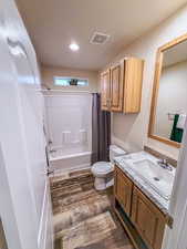 Full bathroom featuring hardwood / wood-style flooring, vanity, toilet, and shower / bath combo