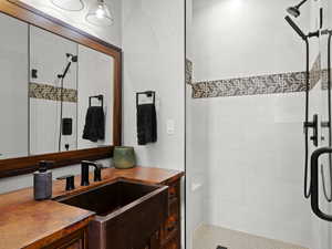 Secondary Bathroom with copper vanity and upgraded tiled shower