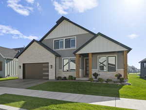 View of front of house with covered porch, a front yard, and a garage