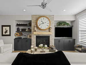 Living room featuring ceiling fan and a stacked stone fireplace.