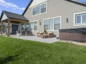 Rear view of property with a patio area, an outdoor hangout area, and yard adjacent to large grassy common area.,