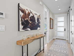 Welcoming brightly lit Entryway featuring light hardwood flooring and a barn door