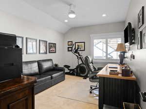 Carpeted Bedroom currently being used as an office with ceiling fan and lofted ceiling.