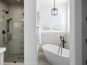 Master Bathroom featuring heated tile patterned flooring, separate shower and tub, and tile walls