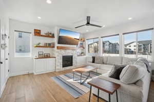 Living room featuring a fireplace, light hardwood / wood-style floors, plenty of natural light, and ceiling fan