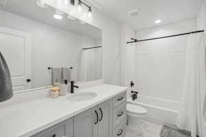 Full bathroom featuring vanity, shower / bath combination with curtain, and toilet