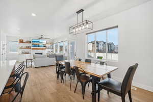 Dining area featuring ceiling fan, a stone fireplace, and light wood-type flooring