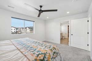 Carpeted bedroom with connected bathroom and ceiling fan