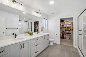 Bathroom featuring toilet, tile patterned flooring, vanity, and walk in shower