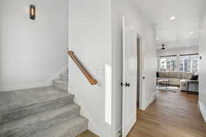 Stairs with ceiling fan and wood-type flooring