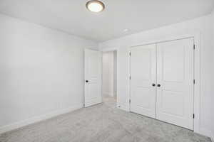 Unfurnished bedroom featuring light colored carpet and a closet