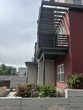 View of side of home featuring fence and a balcony, Front entry with gardens and patio