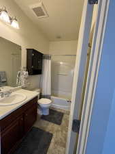 Ensuite full bathroom with shower / bath combo, vanity, and toilet, tile floors.