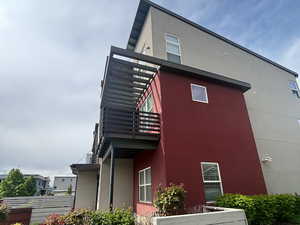 View of home's exterior with stucco siding and a balcony, row end, East facing, View of park across the street. Walk to lake and Harmons.