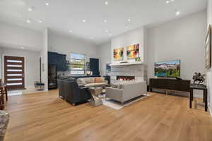 Living room featuring a tiled fireplace, a towering ceiling, and light hardwood / wood-style floors