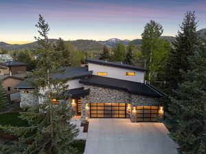 Contemporary home with stone siding, a mountain view, a garage, concrete driveway, and stucco siding