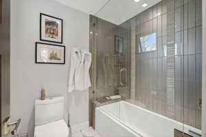 Bathroom featuring tile patterned flooring, toilet, and shower / bath combination with glass door