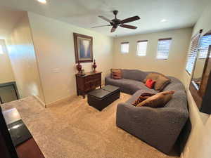 Carpeted living room with ceiling fan