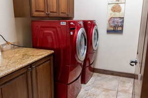 Washroom featuring cabinets, light tile patterned floors, and washing machine and dryer