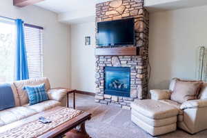 Carpeted living room featuring a stone fireplace