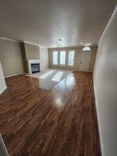 Unfurnished living room featuring dark hardwood / wood-style flooring and crown molding