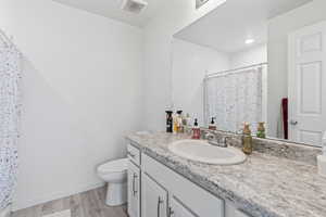 Bathroom featuring hardwood / wood-style flooring, vanity, curtained shower, and toilet