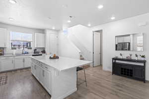 Kitchen featuring white cabinets, stainless steel refrigerator with ice dispenser, light hardwood / wood-style floors, and a kitchen island