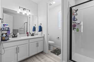 Bathroom featuring wood-type flooring, vanity, toilet, and walk in shower