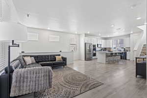 Living room featuring a textured ceiling, light wood-type flooring, and a healthy amount of sunlight