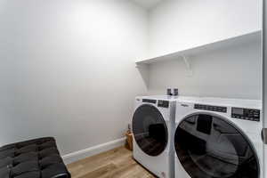 Laundry room with washing machine and clothes dryer and light wood-type flooring