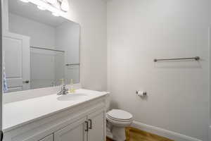 Bathroom with hardwood / wood-style floors, vanity, toilet, and a shower