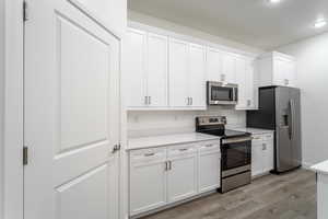 Kitchen featuring white cabinets, appliances with stainless steel finishes, and light wood-type flooring