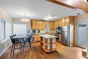 Kitchen featuring decorative light fixtures, stainless steel appliances, light hardwood / wood-style floors, and sink