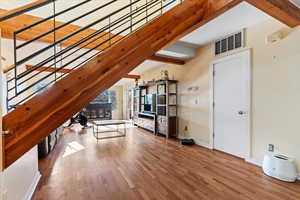 Unfurnished living room featuring hardwood / wood-style floors and beam ceiling