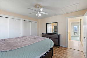 Bedroom featuring ceiling fan, multiple closets, and light hardwood / wood-style flooring