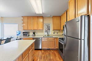 Kitchen with stainless steel appliances, light hardwood / wood-style flooring, and sink