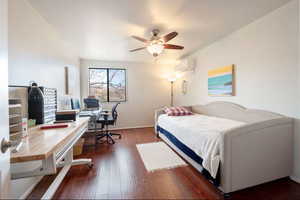 Bedroom with ceiling fan, dark hardwood / wood-style flooring, and an AC wall unit