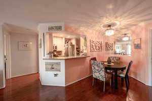 Dining room with ornamental molding, dark hardwood / wood-style floors, and a notable chandelier