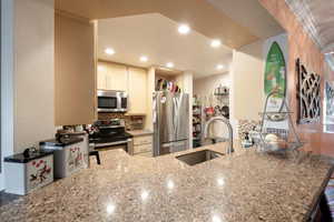 Kitchen with kitchen peninsula, sink, ornamental molding, and appliances with stainless steel finishes