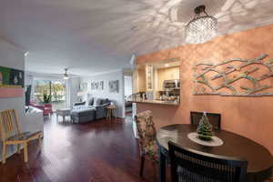 Dining area with dark hardwood / wood-style floors, crown molding, and ceiling fan with notable chandelier