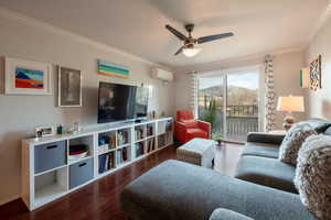 Living room featuring dark hardwood / wood-style floors, ceiling fan, crown molding, and a wall mounted AC