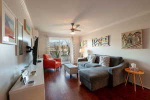 Living room with a wall unit AC, ceiling fan, dark hardwood / wood-style floors, and ornamental molding