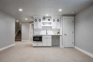 Kitchen with light colored carpet, white cabinetry, and stainless steel microwave