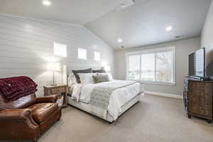 Carpeted bedroom with wood walls and vaulted ceiling