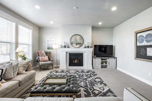 Carpeted living room featuring a fireplace and a textured ceiling