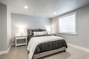 Bedroom with light colored carpet and a textured ceiling