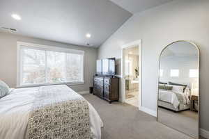 Carpeted bedroom with ensuite bathroom and lofted ceiling