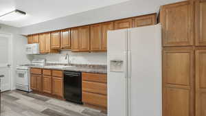 Kitchen featuring light wood-type flooring, white appliances, and sink